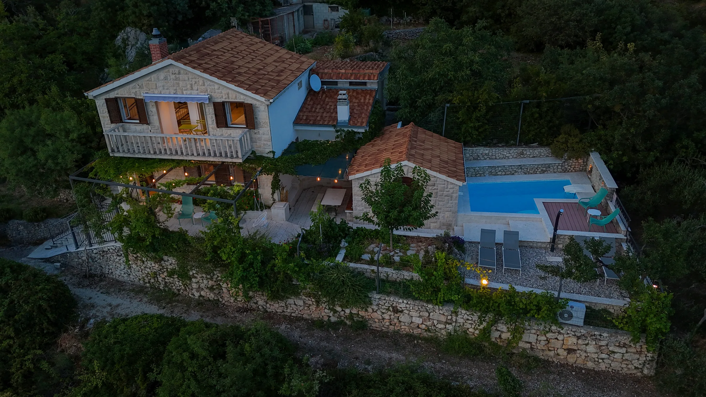 Aerial view of Villa Dalmatia and its illuminated pool after sunset